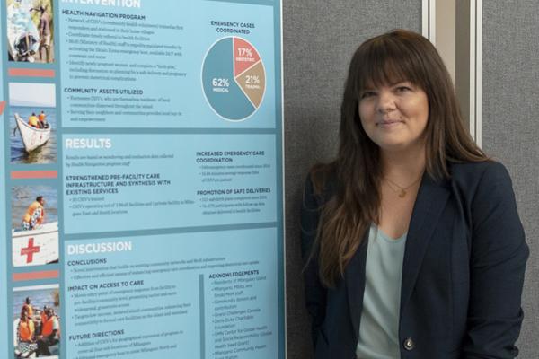 A woman stands next to her research poster
