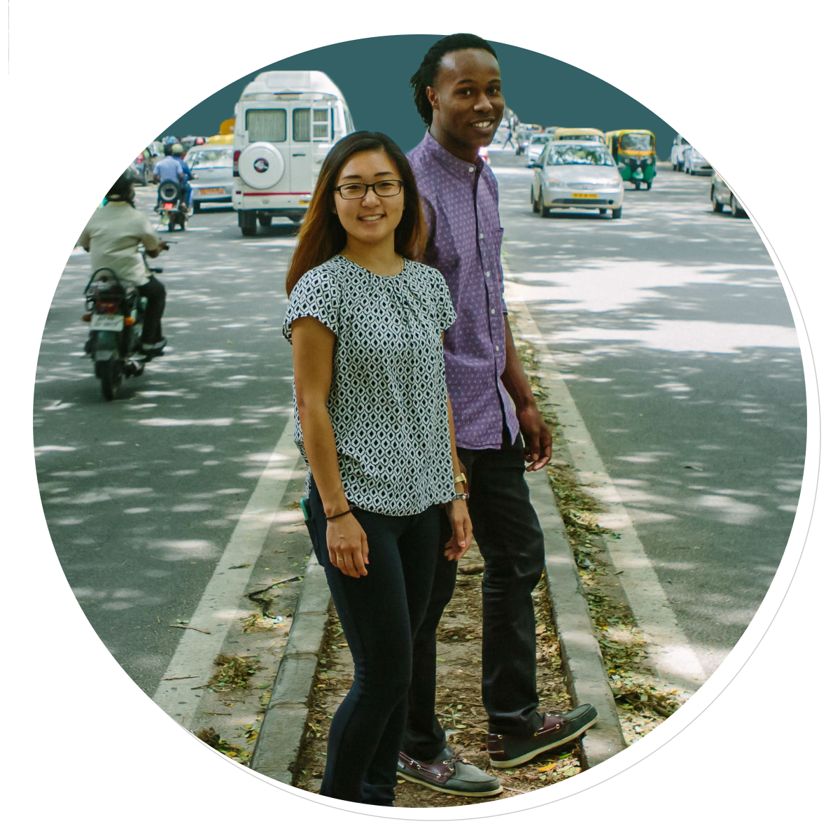 Two people stand in the median of a road
