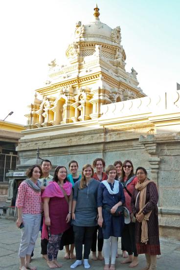 Students in the 2018 Mysore course stand looking at the camera with a large temple behind them