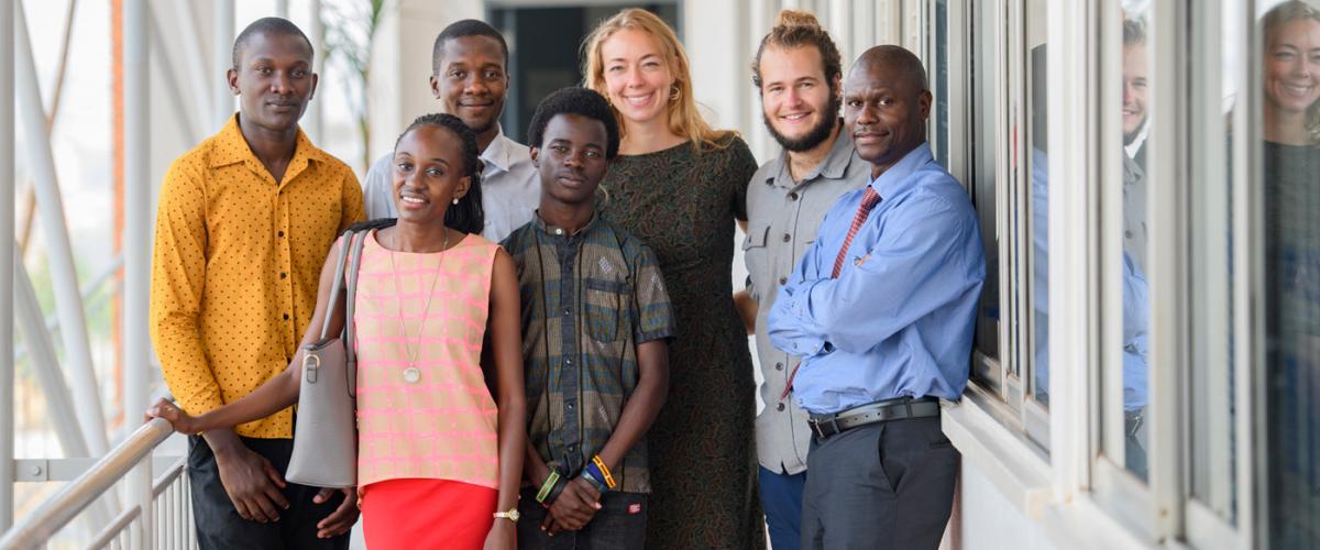 A group of health professionals in East Africa stand next to each other and smile at the camera