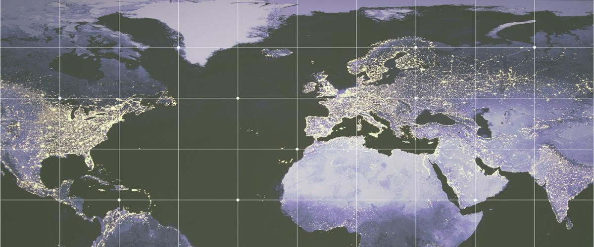 The world at night with lights from major cities creating a web across continents. A crosshatch of white grid lines is overlaid on the globe image.