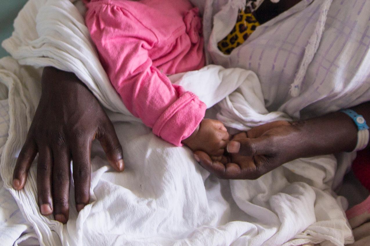 A mom holds her baby's hands in a hospital in Ethiopia