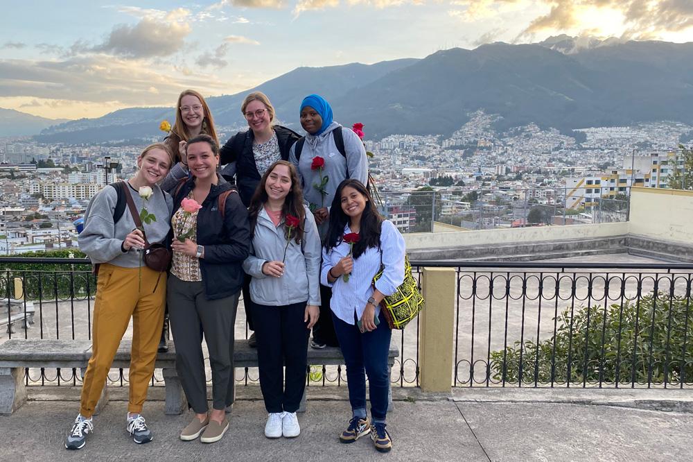 Group of students stand in front of a mountainous background in Quito,Ecuador smiling toward the camera