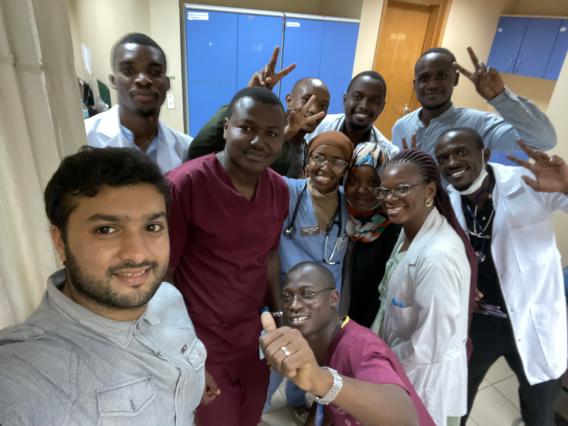 Hamdi Sheikhsaid stands with other health professionals in a hospital, all smiling at the camera